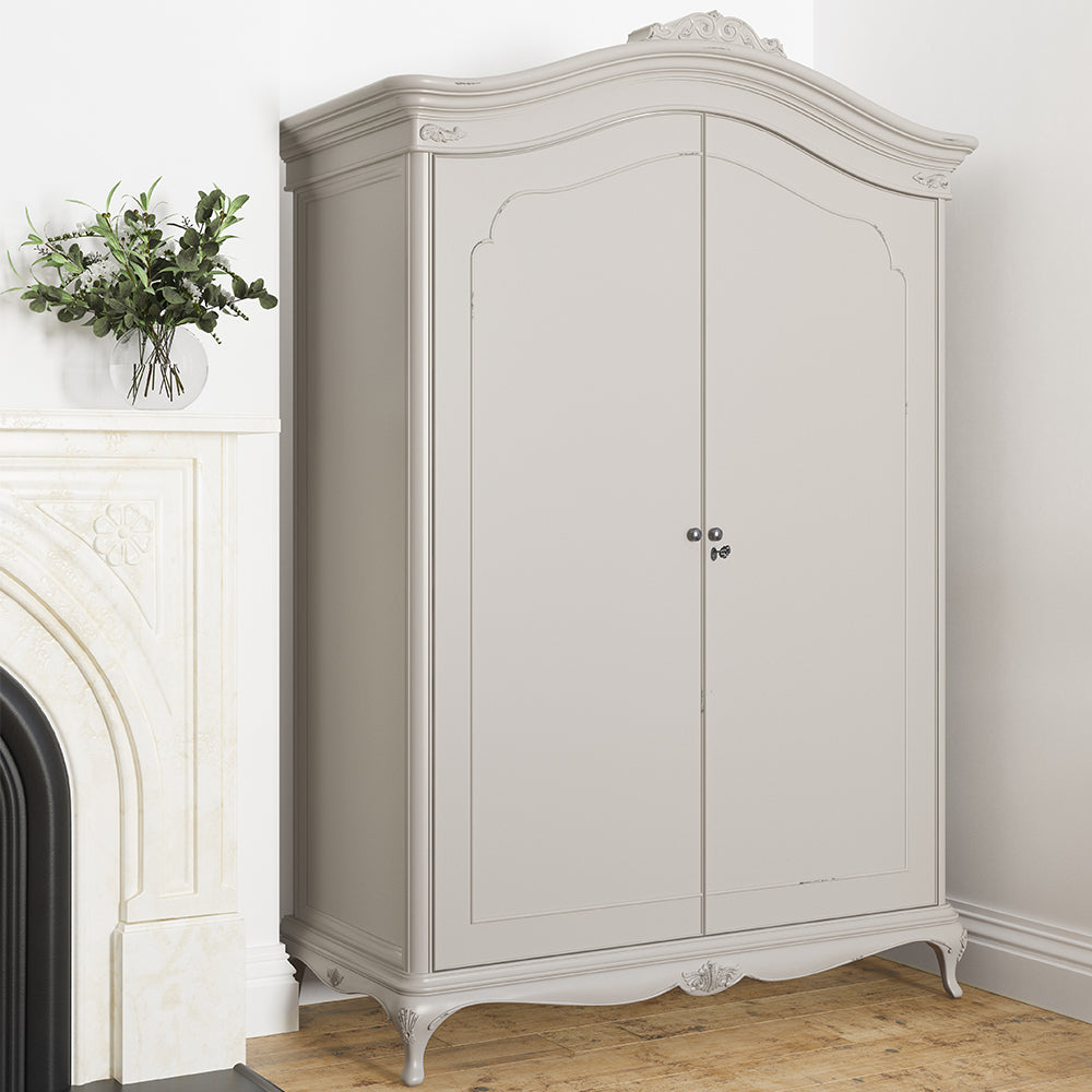 A closed soft grey wardrobe with curved top and ornate crown, featuring double doors and decorative legs
