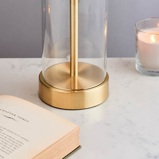 Simple  table light with a clear glass base, vintage white faux silk shade and a brushed gold effect finish